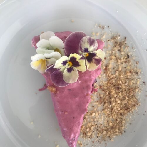 cheesecake with raspberry sauce, crushed almonds and edible flowers