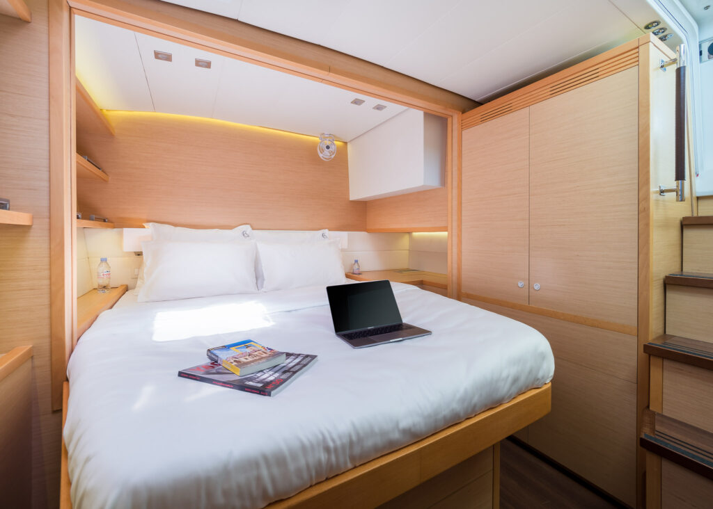 Ensuit cabin with a double bed with magazines and laptop.